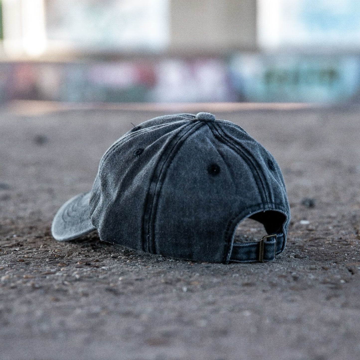 Achterkant van een grijs gewassen denim kinderpet op een betonnen ondergrond in streetstyle setting.