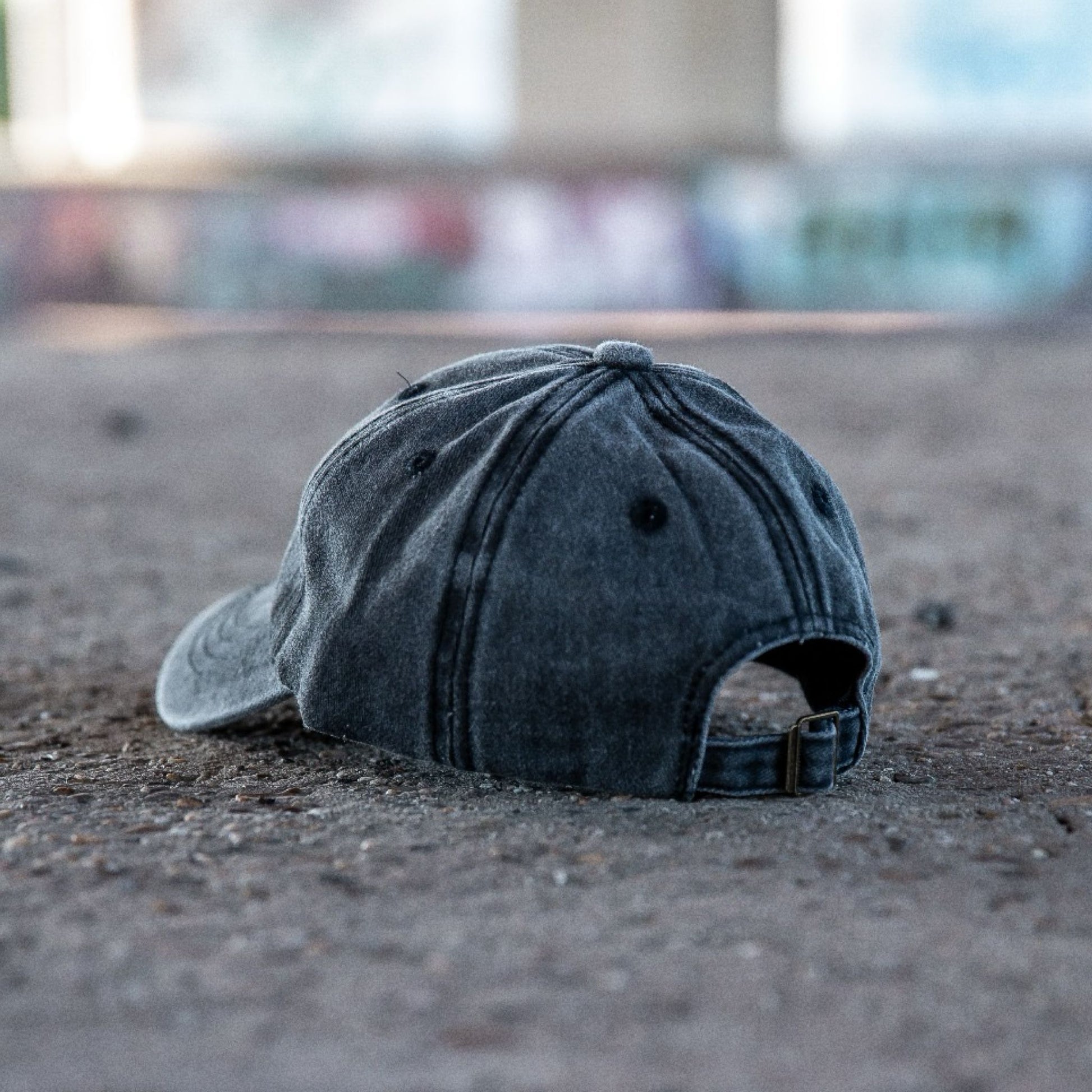 Achterkant van een grijs gewassen denim kinderpet op een betonnen ondergrond in streetstyle setting.